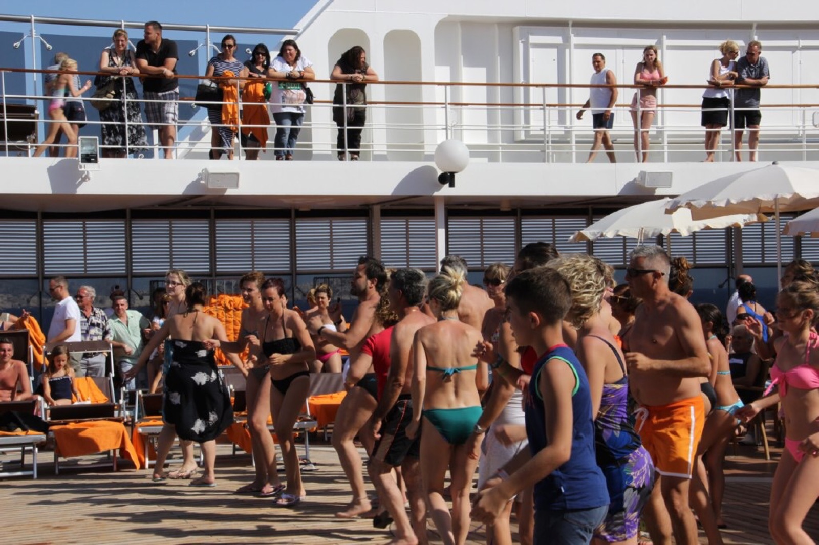 A cruise ship pool deck lined with sun loungers on a bright sea day.