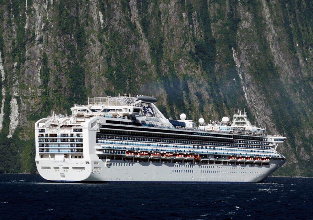 A cruise ship dwarfed by the sheer cliffs of Milford Sound, New Zealand.